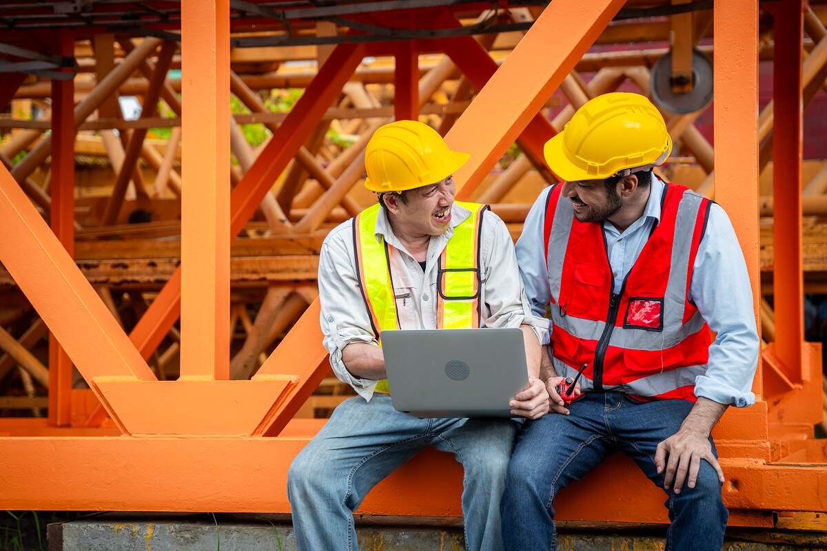two-men-safety-gear-are-looking-piece-of-machinery-ZYHQQB5.jpg